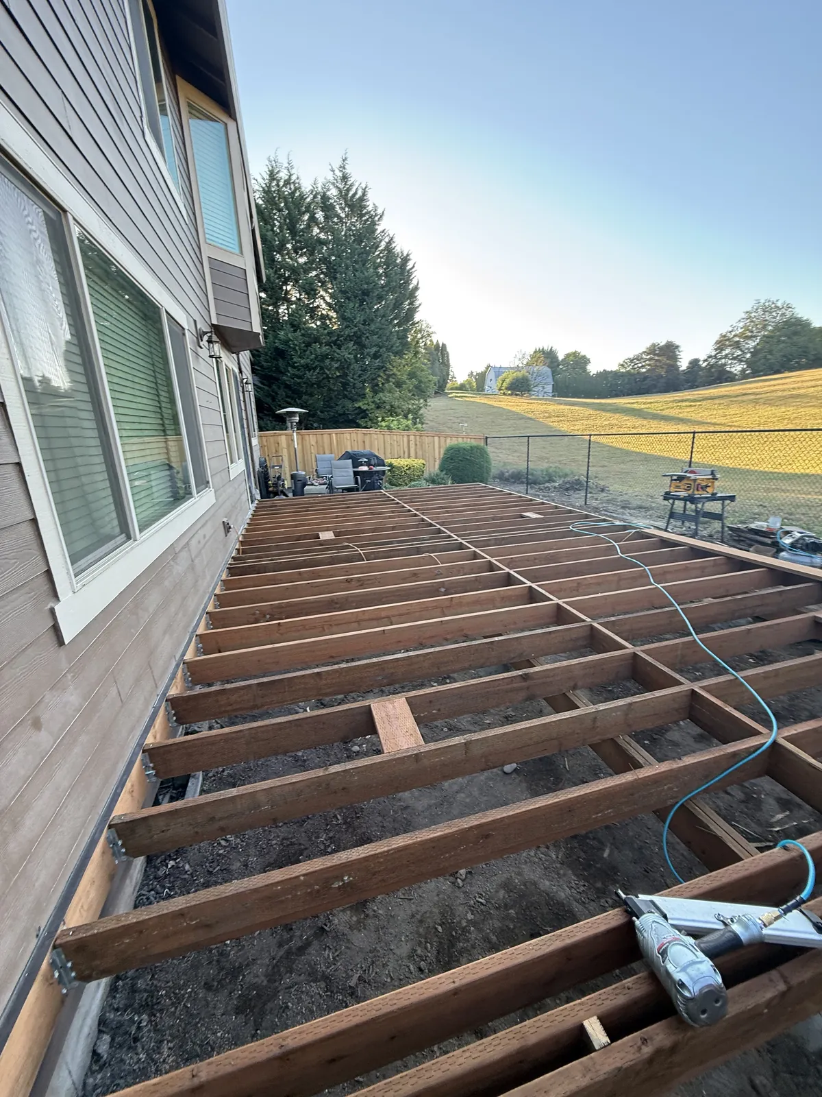 Deck under construction with the joists and beam in place and the boards not yet laid, seen from the yard