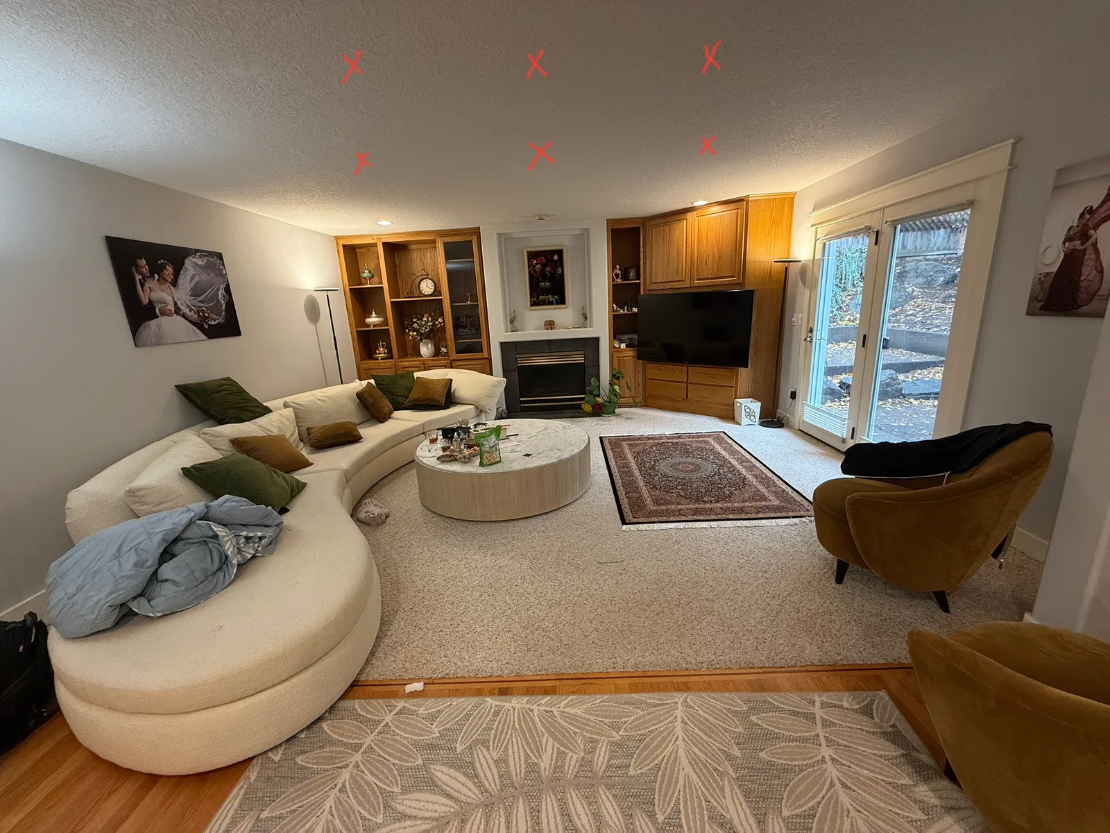 Living room before the remodel with oak built-ins either side of the fireplace, a textured ceiling and marks on it where new lights will go