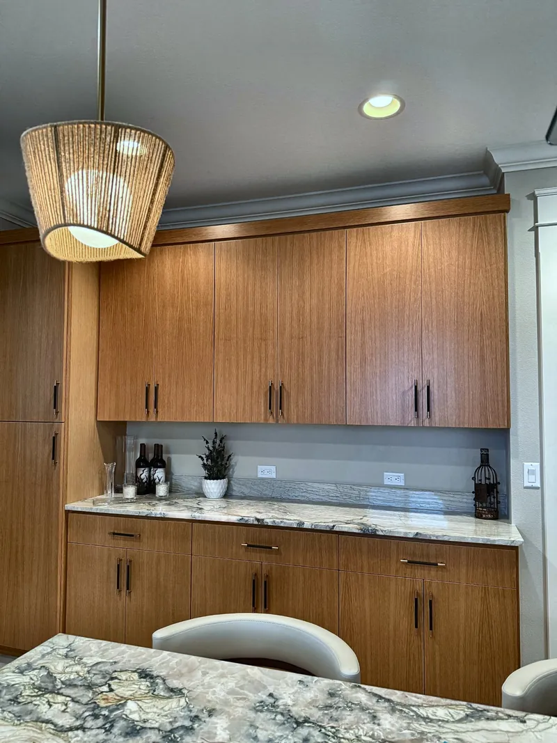 Wood cabinets and a patterned stone counter under a woven pendant