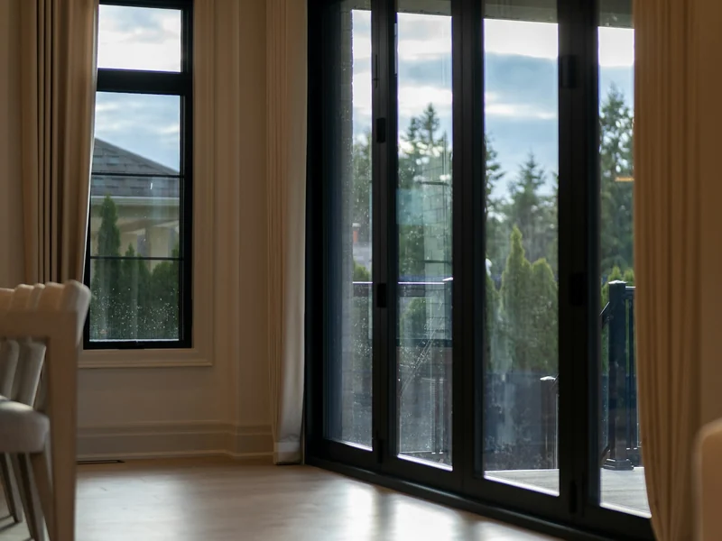 Wide sliding doors opening from a gray sided home onto a patio
