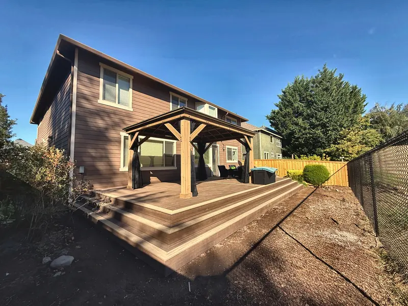 Finished cedar deck with a timber-framed patio cover and wide steps down to the yard