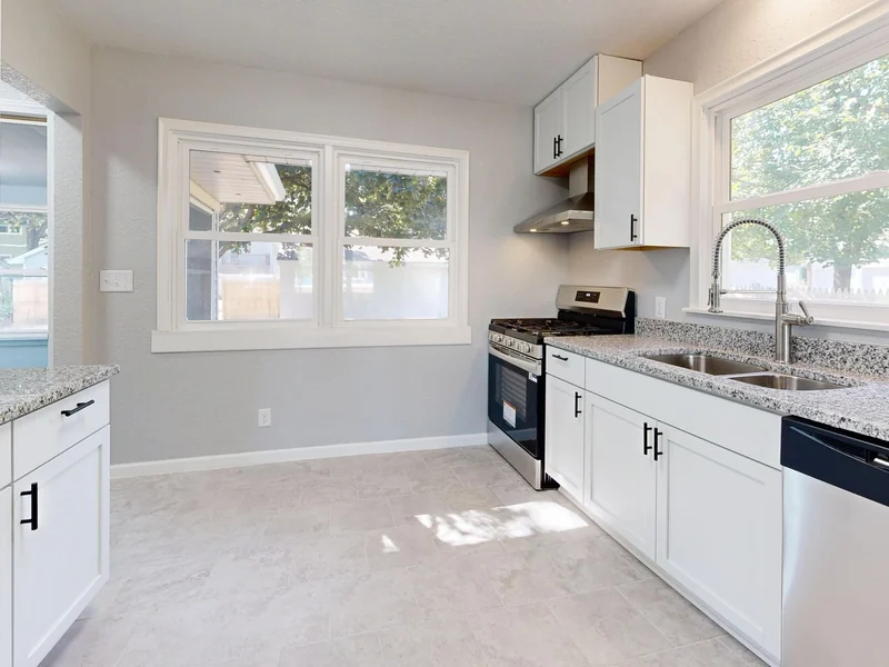 Renovated kitchen with white shaker cabinets, granite counters, a stainless range and an undermount double sink