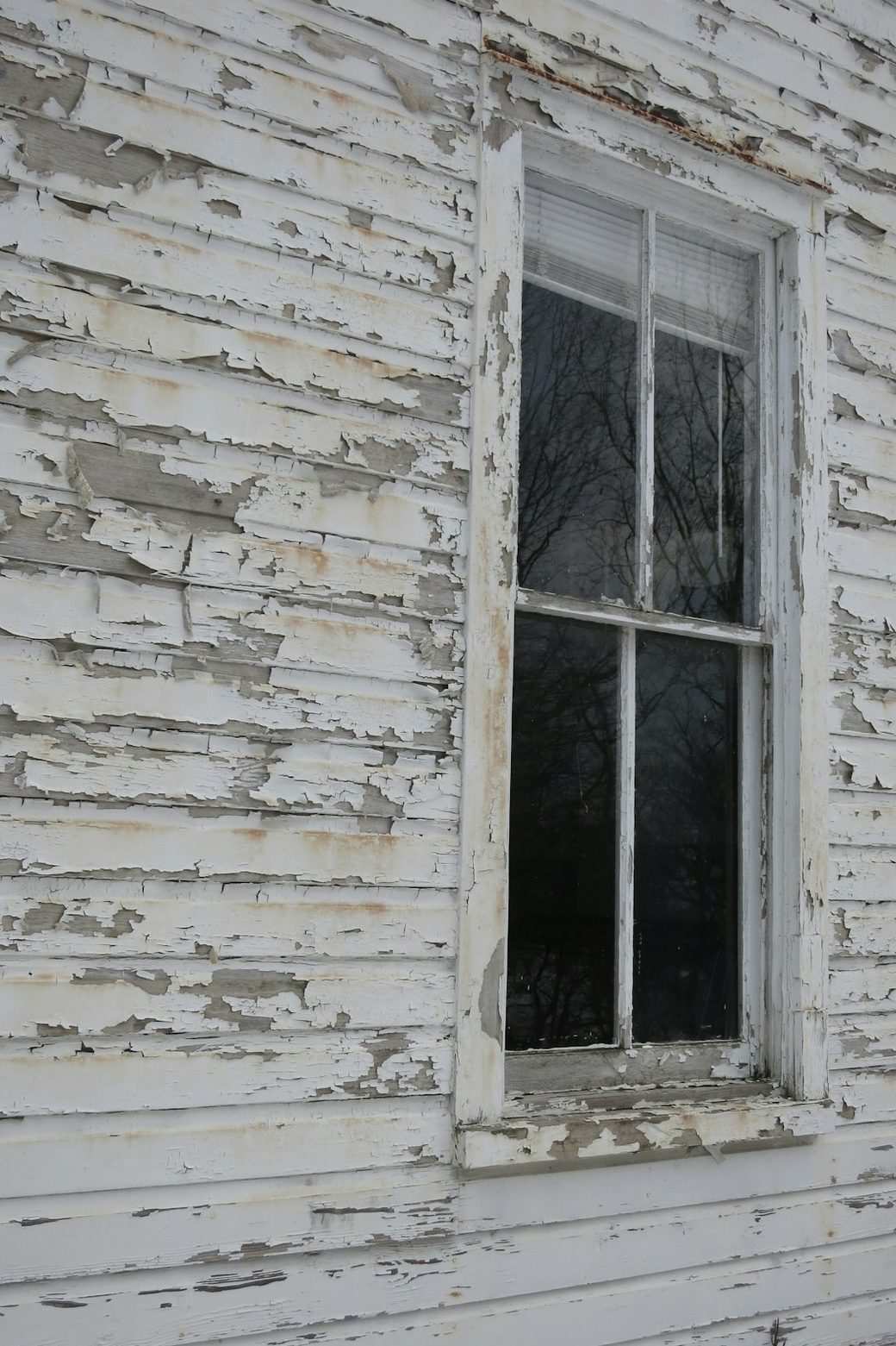 Peeling paint on old wood window trim and siding