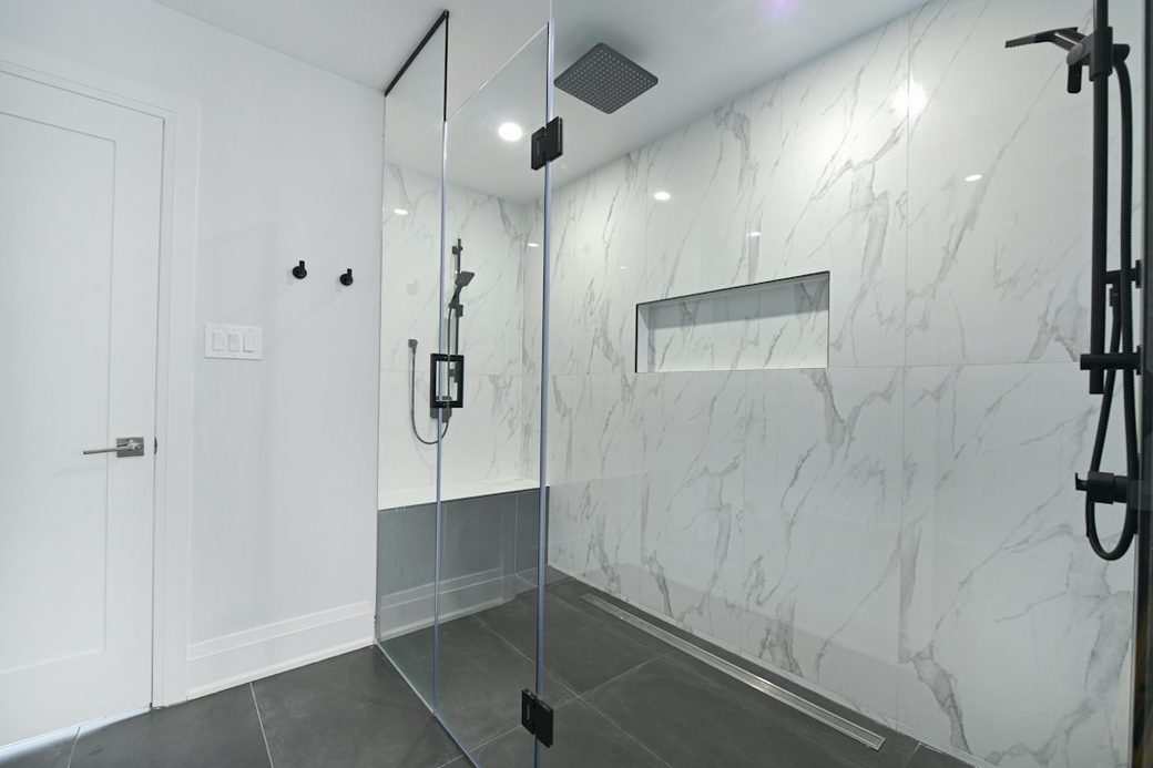 Walk-in glass shower with marble tile