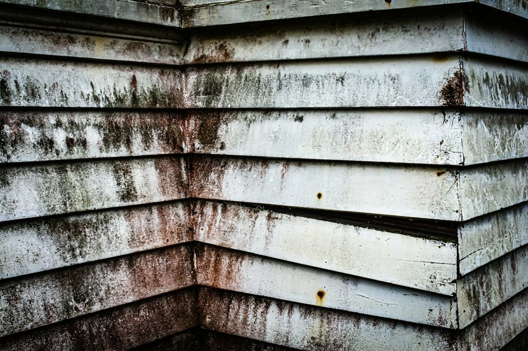 Weathered wood siding corner with staining