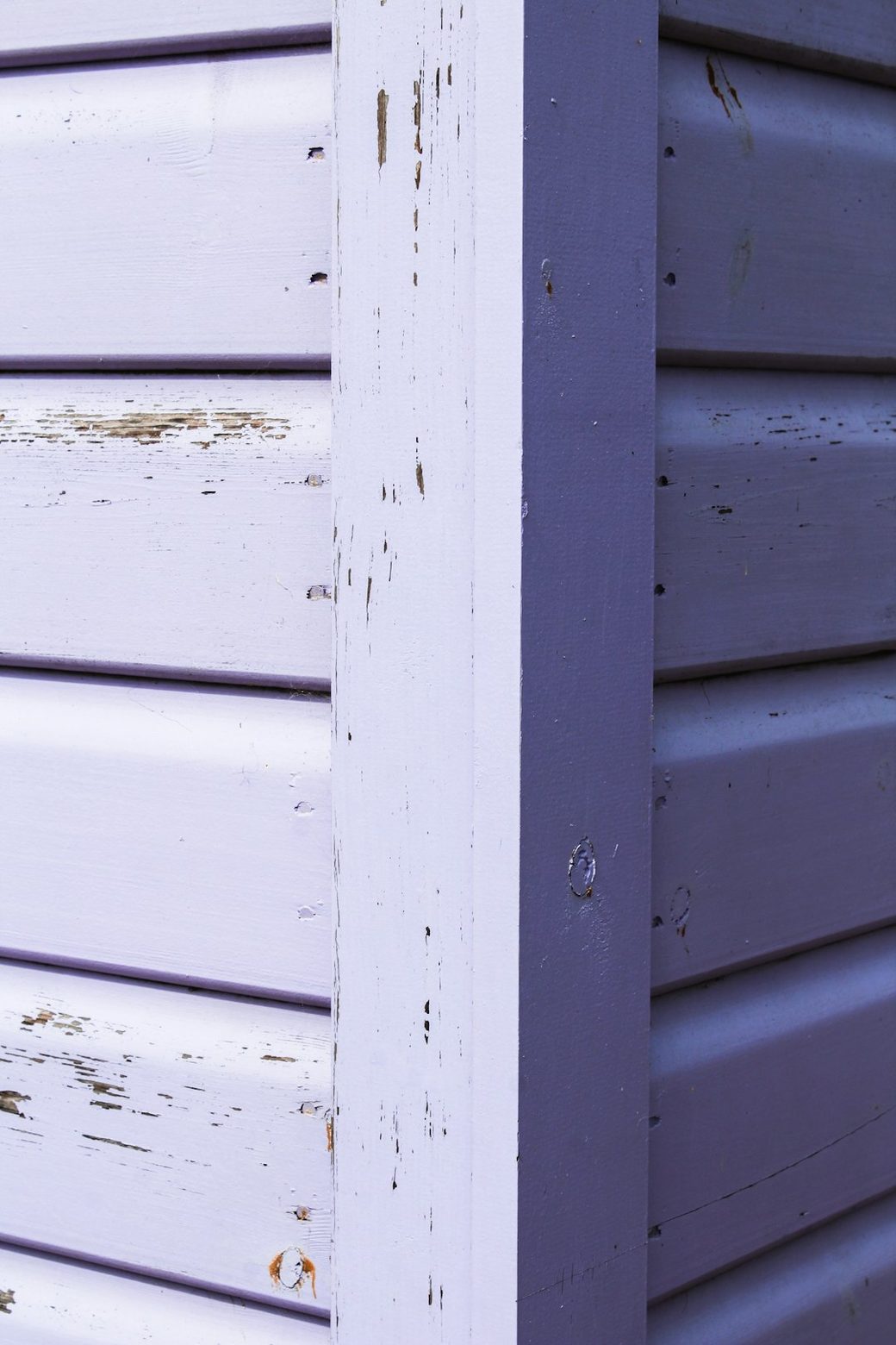Closeup of weathered painted wood siding corner