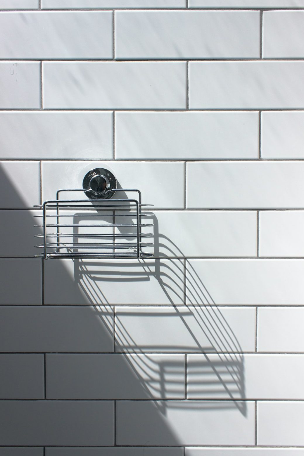 Closeup of white tile shower wall with caddy
