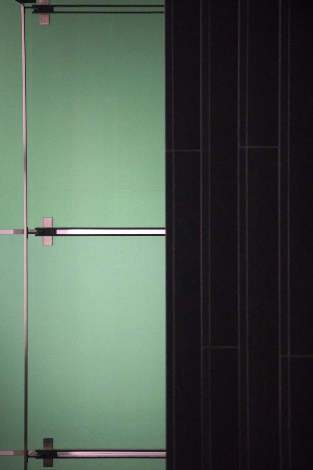 Dark green tiled shower with chrome fixture