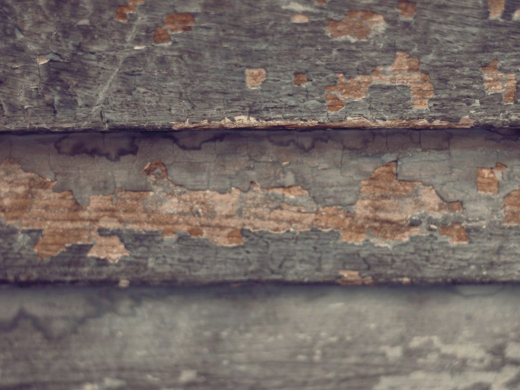 Closeup of peeling paint on weathered wood siding